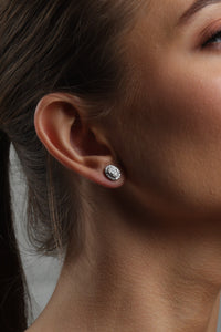 Woman wearing earrings and a necklace, posing with hand near face.
