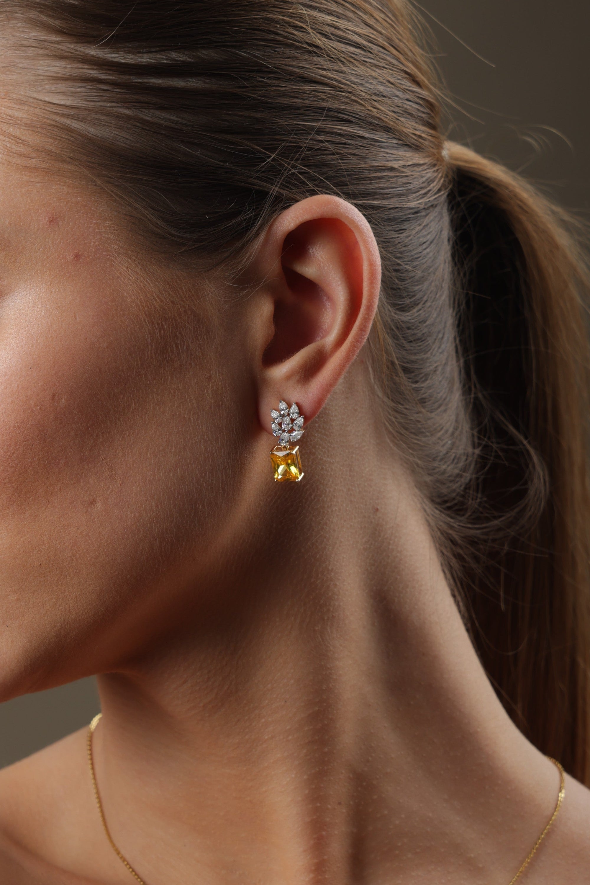 Woman wearing gold jewelry against a brown background