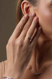 Woman wearing a gold necklace against a brown background