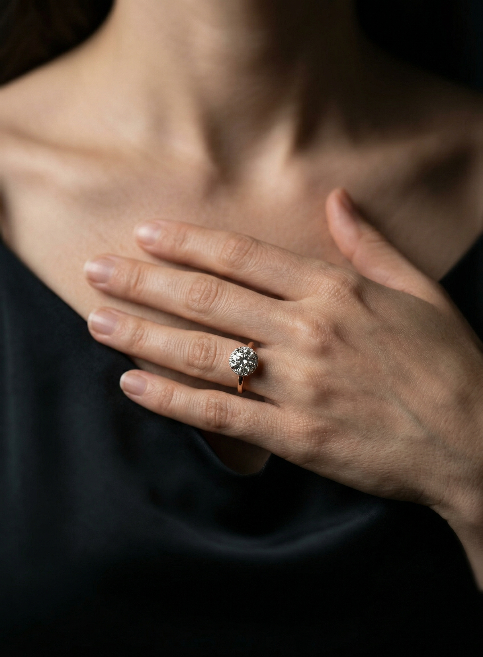 Close-up of a hand wearing a diamond ring on a dark background