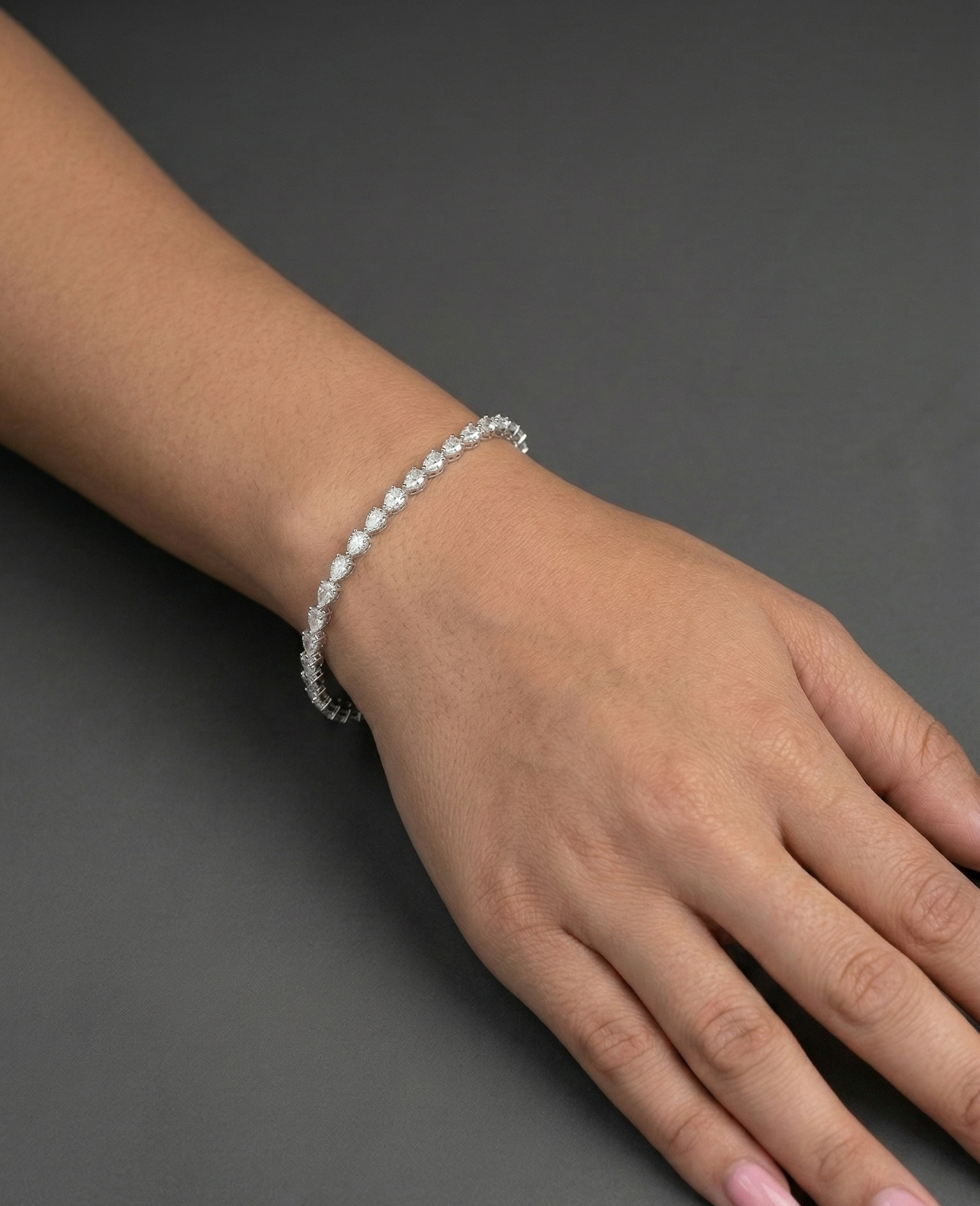Hand wearing a bracelet on a dark background